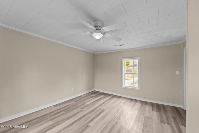 empty room featuring baseboards, crown molding, visible vents, and light wood finished floors