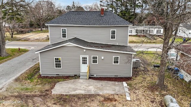 rear view of house with a shingled roof, entry steps, and crawl space