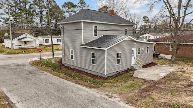 rear view of property with a shingled roof, entry steps, crawl space, and a chimney