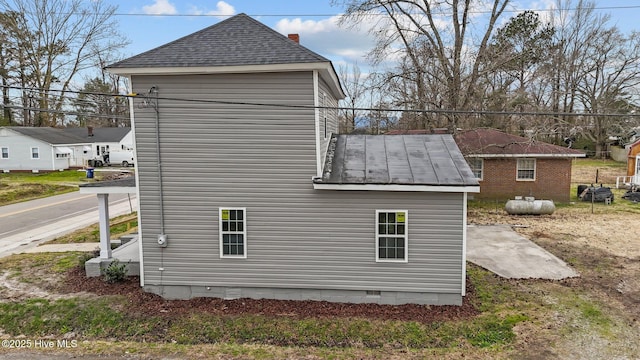 view of side of home with crawl space, roof with shingles, metal roof, and a standing seam roof