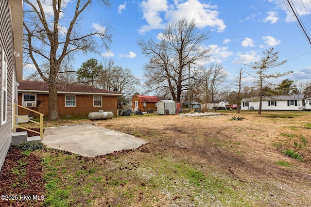 view of yard with an outbuilding, a patio, and a storage unit