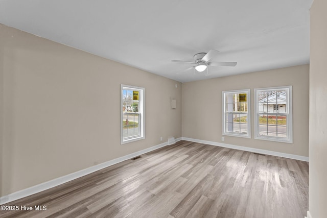 spare room with light wood-type flooring, baseboards, visible vents, and a ceiling fan