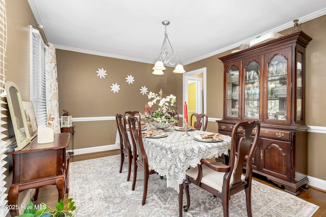 dining room with an inviting chandelier, wood-type flooring, and ornamental molding