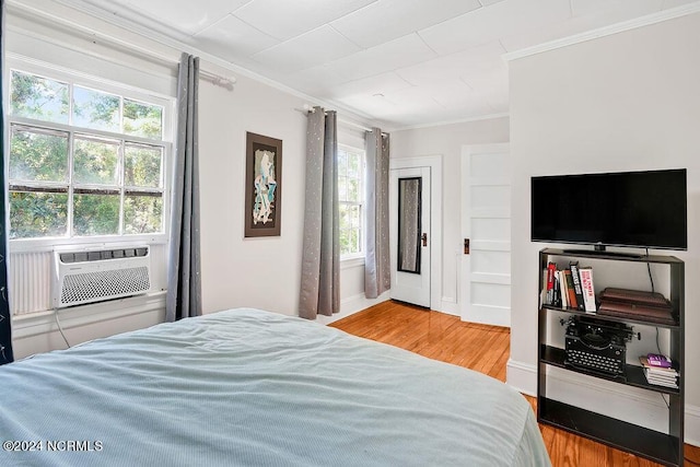 bedroom featuring multiple windows, cooling unit, wood-type flooring, and ornamental molding