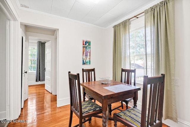 dining area featuring light wood-type flooring, a wealth of natural light, and crown molding