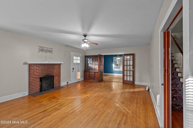 unfurnished living room with hardwood / wood-style flooring, ceiling fan, a fireplace, and french doors