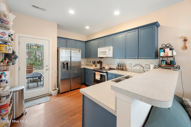 kitchen featuring sink, kitchen peninsula, a breakfast bar, appliances with stainless steel finishes, and light wood-type flooring