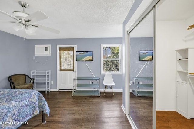 bedroom with baseboards, a textured ceiling, wood finished floors, and a wall unit AC