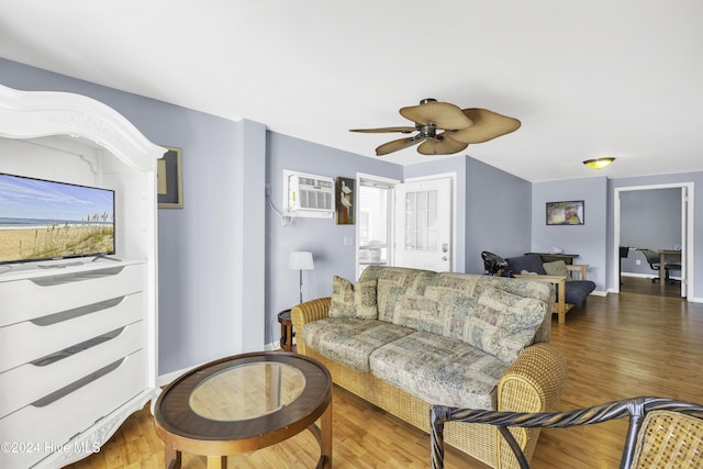 living room featuring baseboards, an AC wall unit, a ceiling fan, and wood finished floors