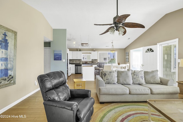 living area featuring baseboards, lofted ceiling, light wood-style floors, and ceiling fan