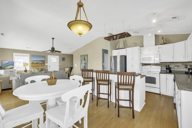 dining space featuring light wood finished floors, visible vents, ceiling fan, and vaulted ceiling