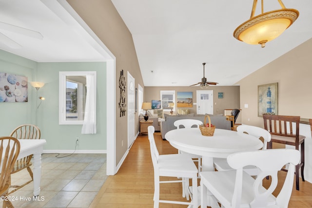 dining area featuring baseboards, lofted ceiling, a ceiling fan, and light wood finished floors