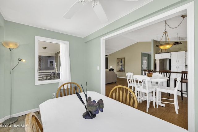 dining room with wood finished floors, a ceiling fan, baseboards, and vaulted ceiling