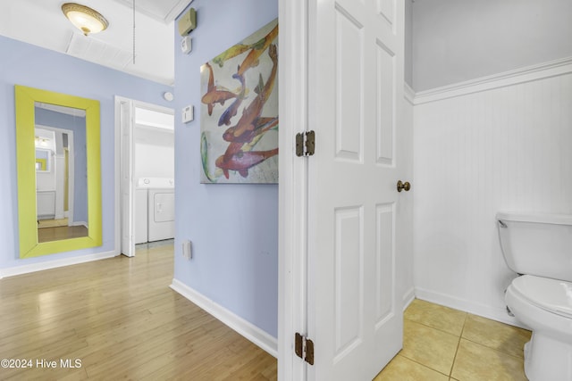 bathroom with hardwood / wood-style flooring, toilet, and independent washer and dryer