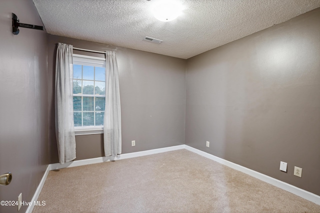 unfurnished room featuring carpet and a textured ceiling