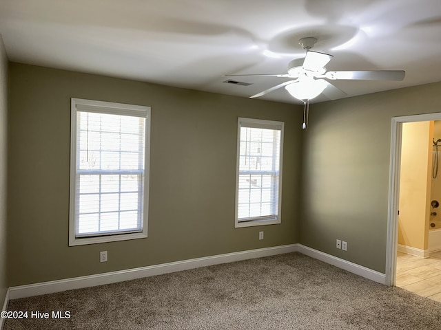 unfurnished room featuring a wealth of natural light, ceiling fan, and light colored carpet