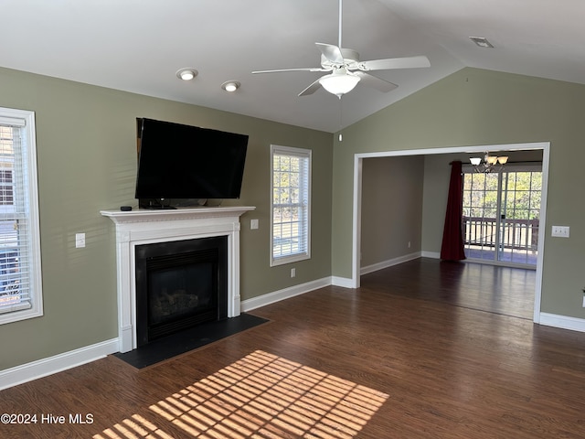 unfurnished living room featuring plenty of natural light, dark hardwood / wood-style flooring, ceiling fan with notable chandelier, and vaulted ceiling