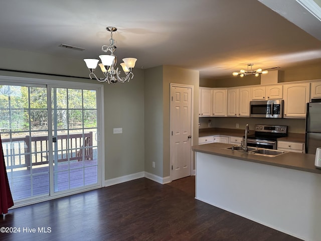 kitchen with dark wood-type flooring, an inviting chandelier, hanging light fixtures, appliances with stainless steel finishes, and white cabinetry