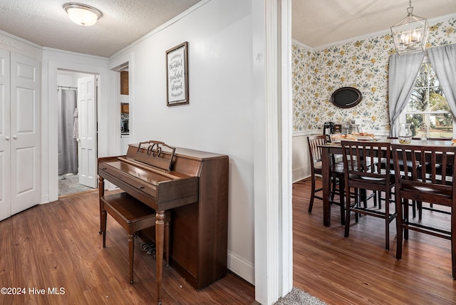 dining room with crown molding, an inviting chandelier, a textured ceiling, and hardwood / wood-style flooring