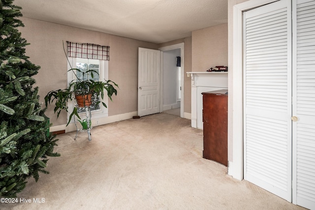 hallway featuring light carpet and a textured ceiling