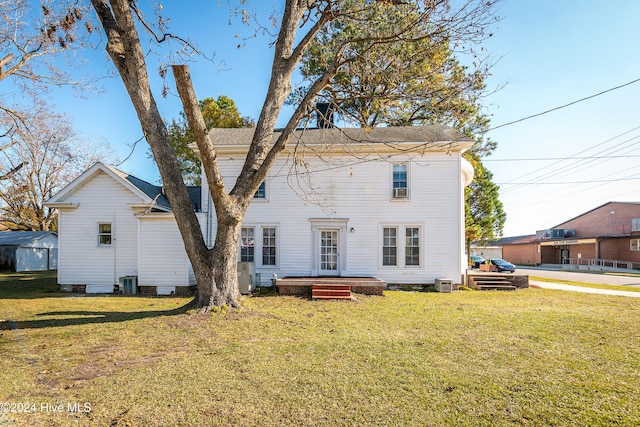 rear view of house with cooling unit and a yard