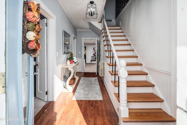 foyer featuring hardwood / wood-style floors, crown molding, and a notable chandelier