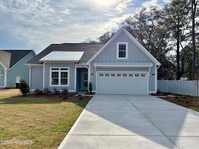 view of front facade with board and batten siding, a front yard, concrete driveway, and fence