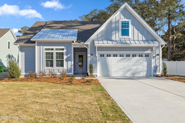 modern farmhouse with a garage, driveway, a front lawn, and board and batten siding