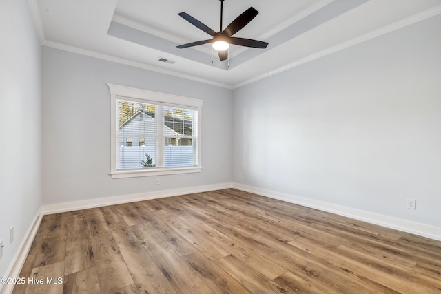 unfurnished room with light wood-style floors, a raised ceiling, visible vents, and baseboards