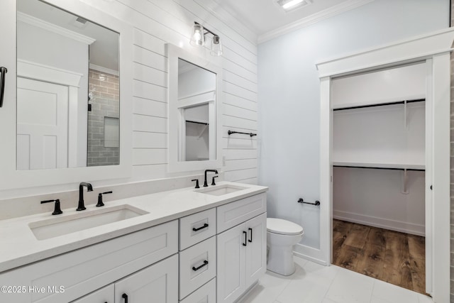 full bathroom with double vanity, a spacious closet, ornamental molding, and a sink