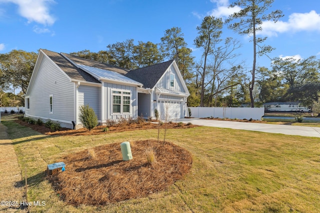 view of front facade with driveway, metal roof, a standing seam roof, fence, and a front yard