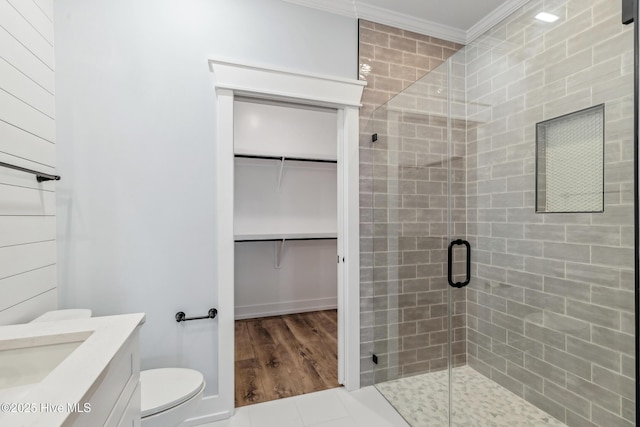 bathroom featuring a walk in closet, toilet, ornamental molding, a shower stall, and vanity