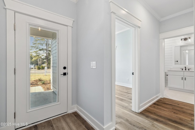 doorway with ornamental molding, a healthy amount of sunlight, baseboards, and wood finished floors