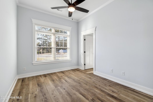 spare room with ornamental molding, wood finished floors, and baseboards