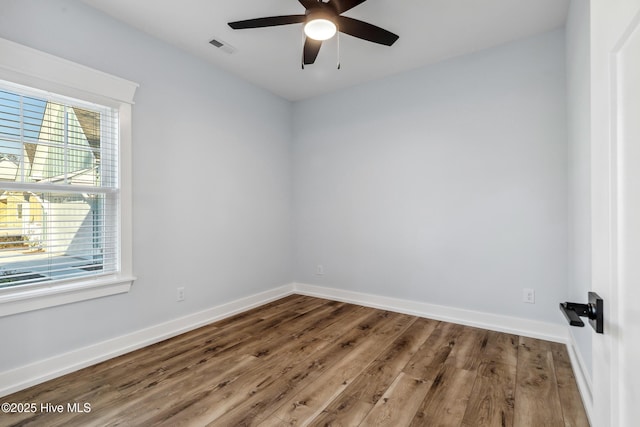 unfurnished room with a ceiling fan, visible vents, baseboards, and wood finished floors