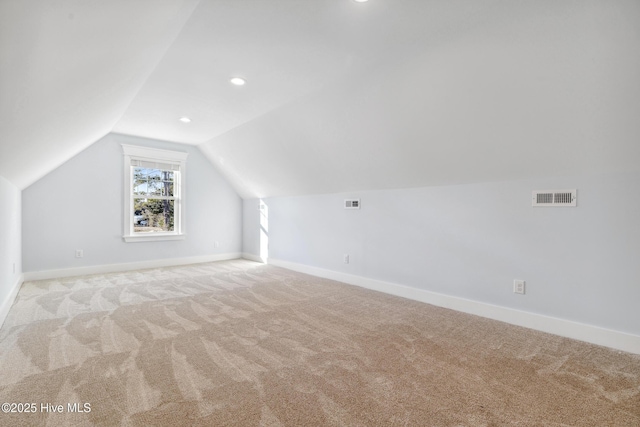 additional living space featuring vaulted ceiling, light carpet, visible vents, and baseboards