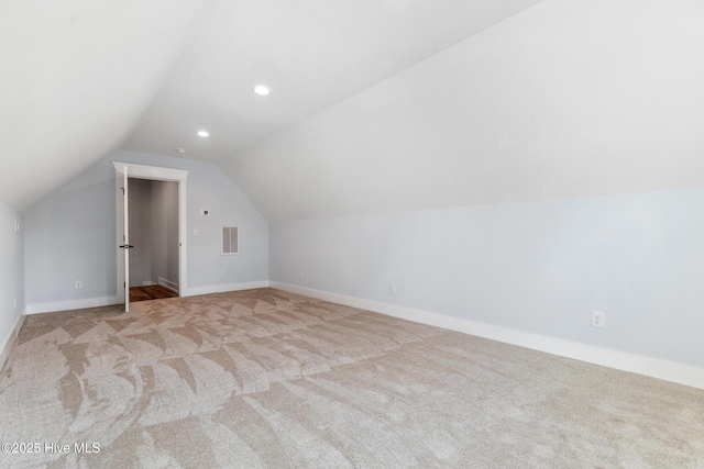 additional living space featuring lofted ceiling, baseboards, light carpet, and visible vents