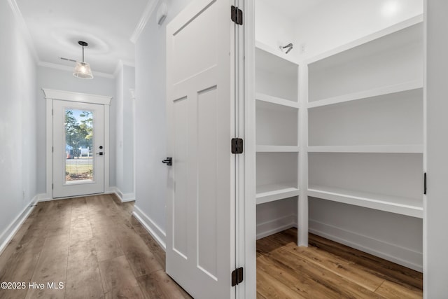 interior space with crown molding, baseboards, and wood finished floors