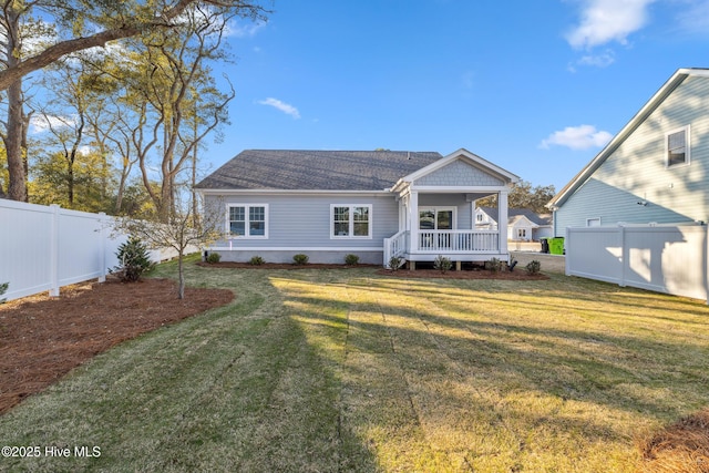 back of house with covered porch, a fenced backyard, and a yard