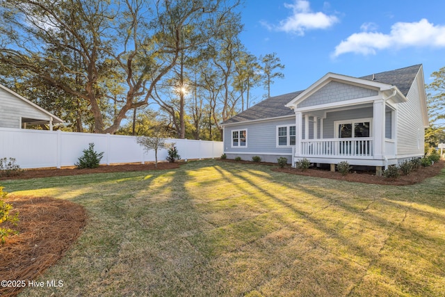 rear view of property featuring a fenced backyard, roof with shingles, and a yard