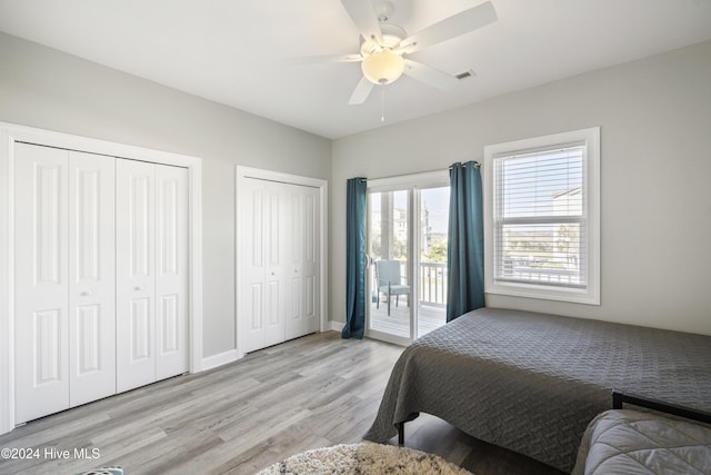 bedroom featuring ceiling fan, access to exterior, light wood-type flooring, and two closets