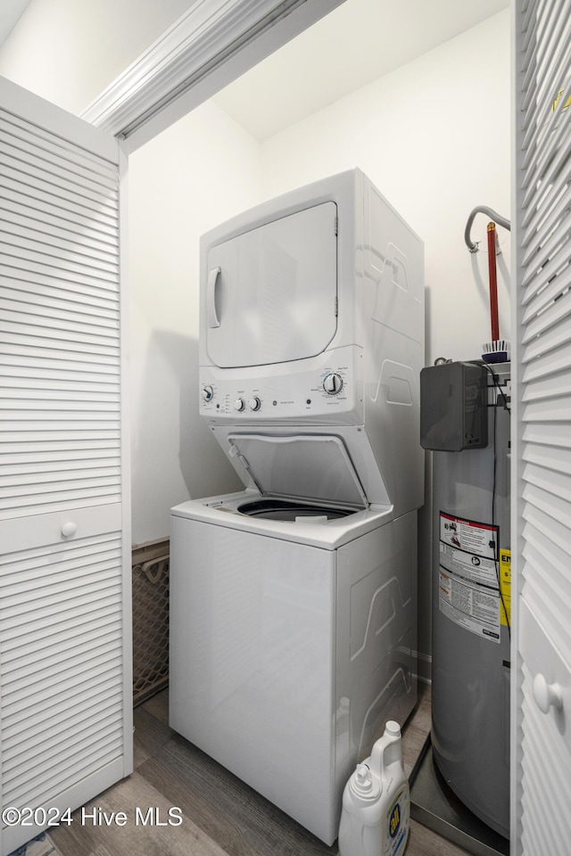 laundry area with water heater, dark hardwood / wood-style floors, and stacked washer and clothes dryer