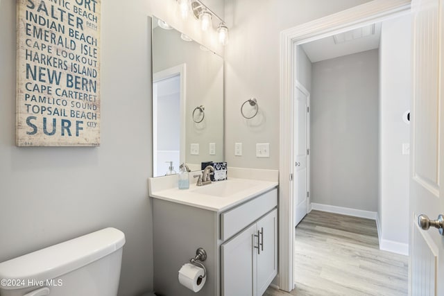 bathroom with wood-type flooring, vanity, and toilet