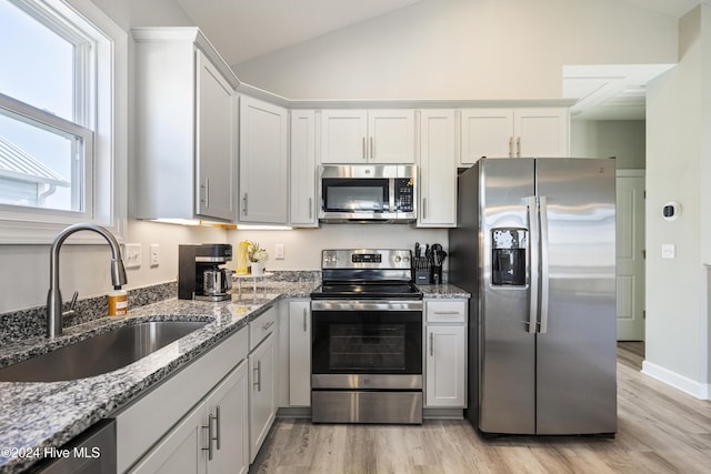 kitchen featuring appliances with stainless steel finishes, light wood-type flooring, lofted ceiling, and sink