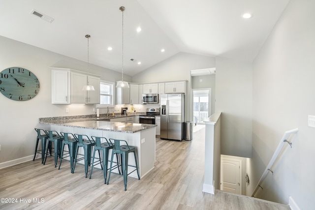 kitchen with white cabinetry, stainless steel appliances, kitchen peninsula, pendant lighting, and light hardwood / wood-style floors