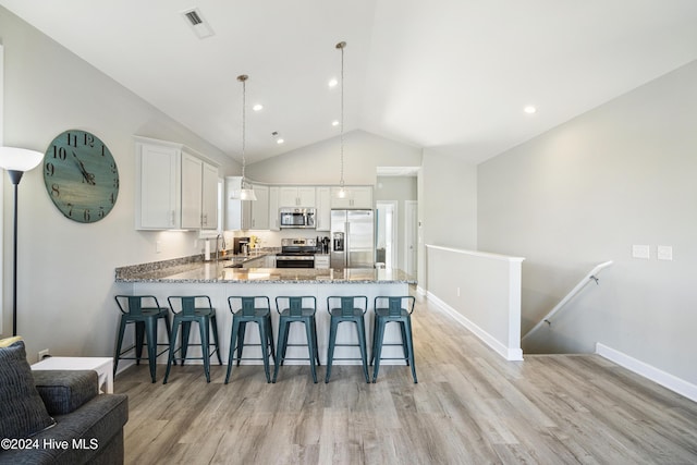 kitchen with pendant lighting, white cabinets, vaulted ceiling, appliances with stainless steel finishes, and kitchen peninsula