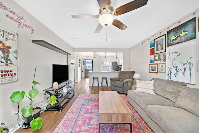 living room featuring ceiling fan, sink, and light hardwood / wood-style flooring