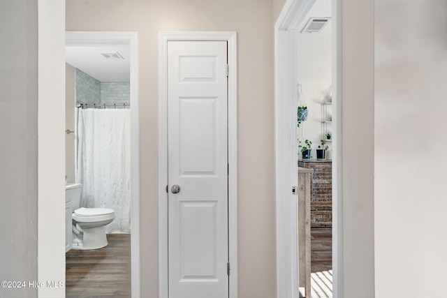 bathroom with hardwood / wood-style floors, toilet, and curtained shower