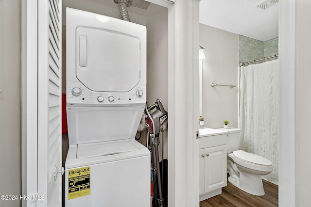 laundry room with hardwood / wood-style floors and stacked washing maching and dryer