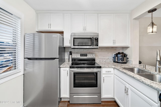 kitchen featuring white cabinetry, sink, stainless steel appliances, decorative light fixtures, and decorative backsplash